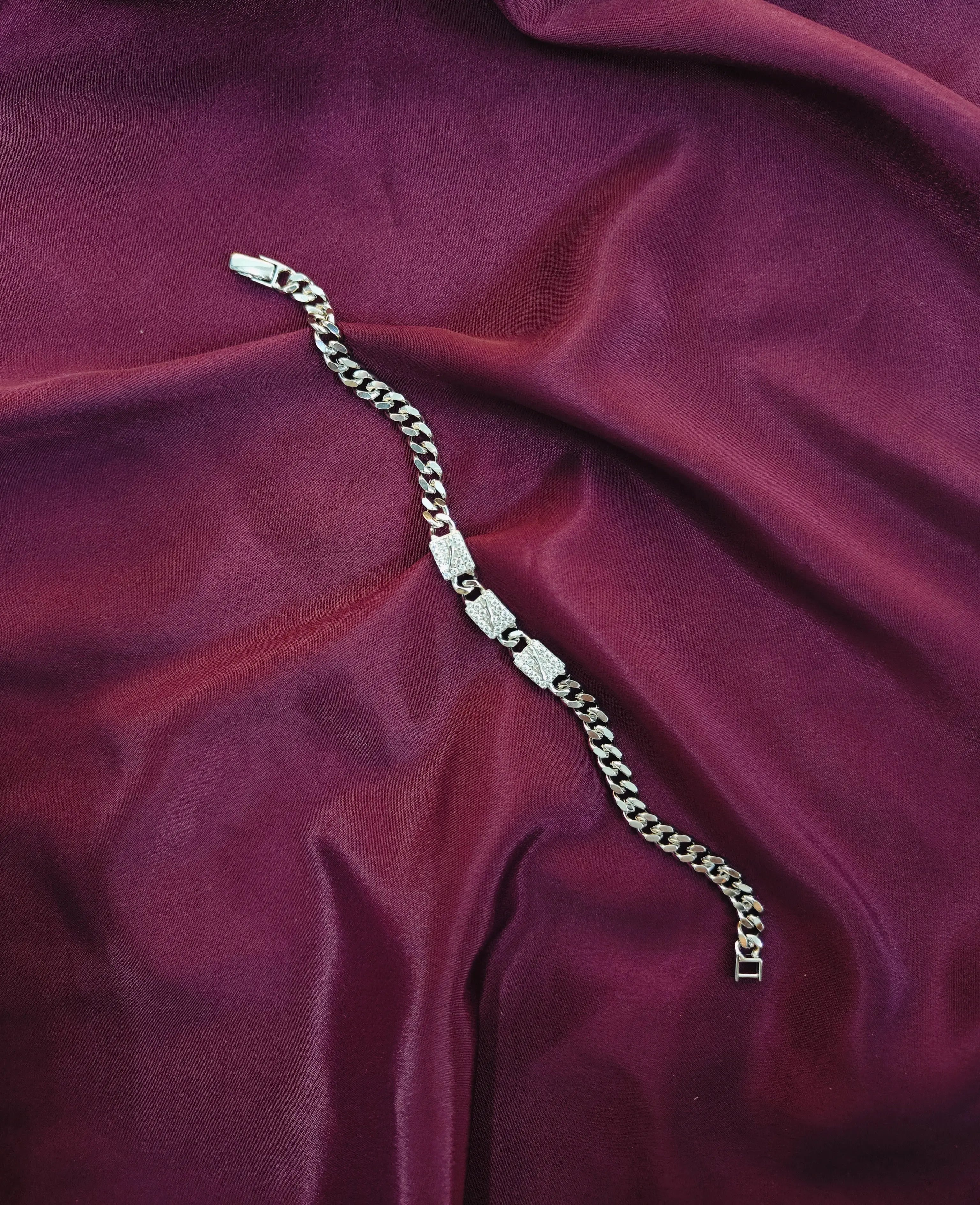 Silver chain bracelet on a purple fabric background
